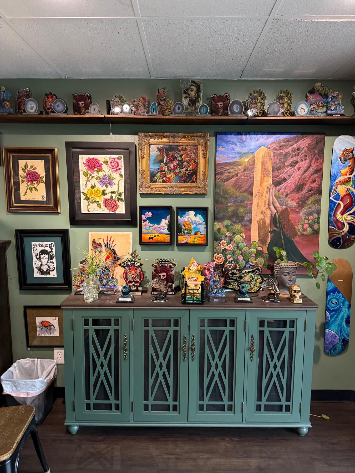 Vintage display cabinet topped with trophies, framed flash art and paintings