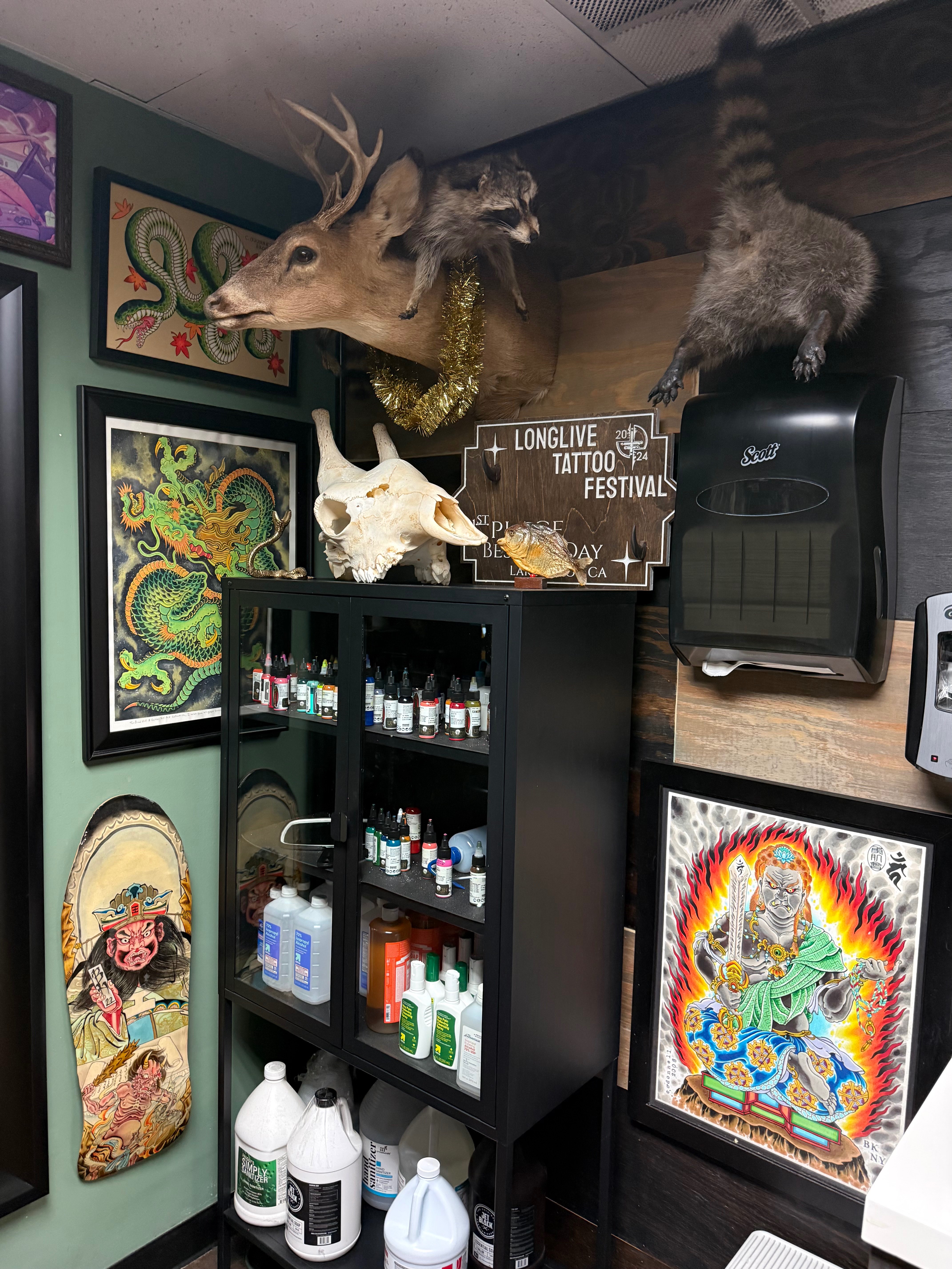 Wide view of the studio floor with tattoo chairs and the full art-covered wall
